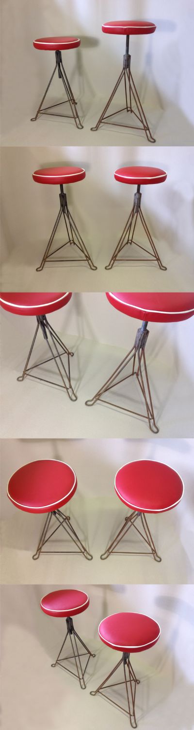 A pair of industrial metal framed stools, c1950s. Adjustable screw down bases. Upholstered in red leather.